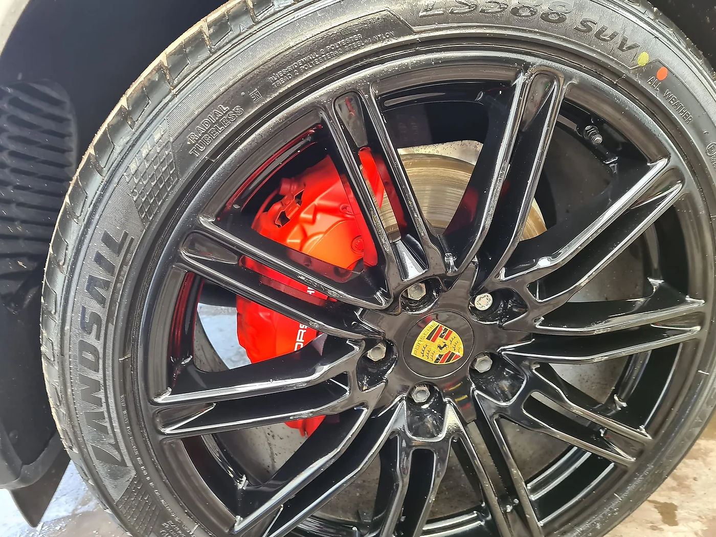 A refurbished gloss-black Porsche alloy wheel with red brake calipers