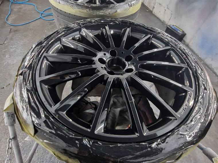 Black multi-spoke alloy wheel masked up for refurbishment