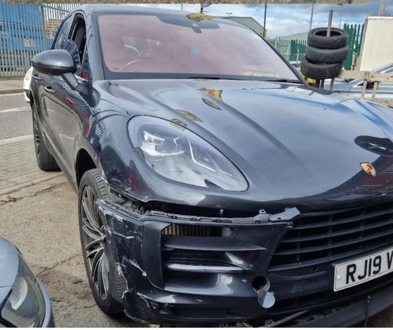 Black Porsche Macan with the front bumper and wing torn open after a collision