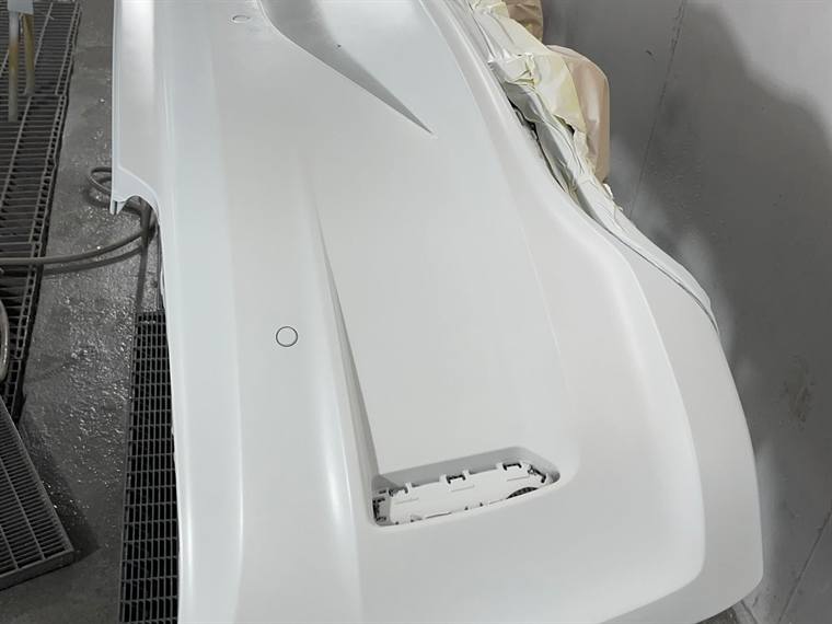 A white bumper freshly sprayed in the booth
