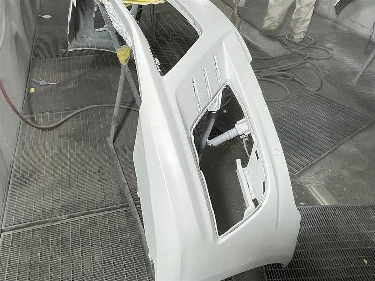 A white door shell in primer inside the spray booth