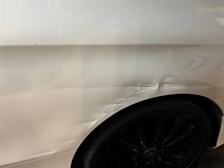 A dent in the rear quarter panel of a cream coloured car