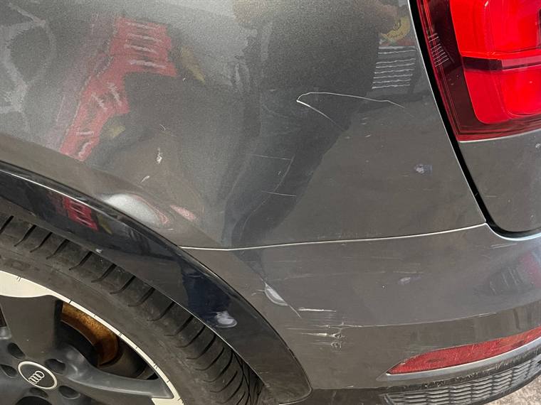 Grey car rear quarter panel scraped through the paintwork