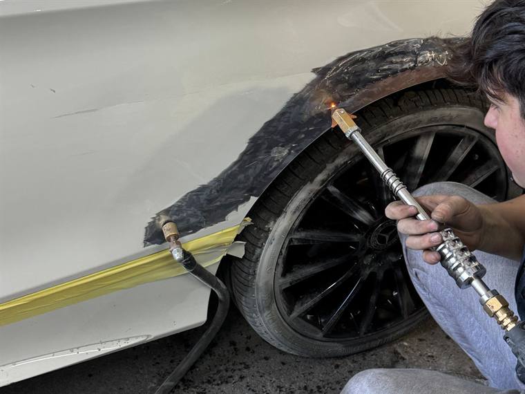 A technician preparing a wheel arch before paint